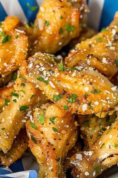 a blue and white bowl filled with chicken wings covered in parmesan sprinkles