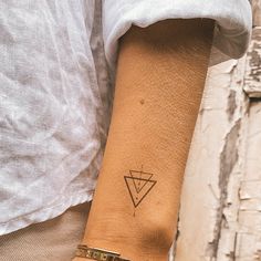 a woman's arm with a small triangle tattoo on the left side of her wrist