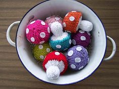 a white bowl filled with knitted balls on top of a wooden table