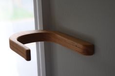 a close up of a wooden door handle on a white wall with a window in the background