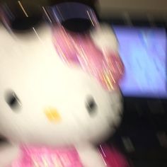 a white hello kitty stuffed animal sitting on top of a table next to a tv