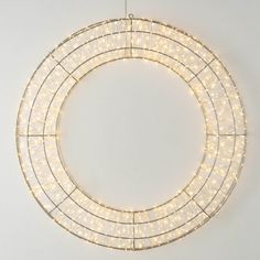 a white wreath with lights hanging from it's sides on a wall in front of a white background