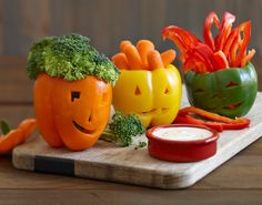 vegetables carved to look like pumpkins on a cutting board with carrots and broccoli