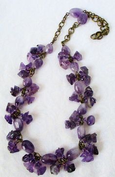 Wear this this charming amethyst & brass necklace to delight your inner earth goddess! 18" in length, made with dark and light purple amethyst stones and chips, purple glass seed beads, and brass chain and lobster clasp. Stone links and dangles made by hand. Finish the look with the matching amethyst & brass bracelet and earrings. This amethyst & brass necklace ships to you in a gift box, ready to give as a present or to keep and store. Back to Beaded Necklaces Amethyst Chips Necklace, Unique Beaded Amethyst Necklace, Gold Amethyst Crystal Necklace With Faceted Beads, Purple Briolette Amethyst Necklace, Inner Earth, Chip Necklace, Gold Amethyst Crystal Necklace, Faceted, Earth Goddess, Amethyst Stones