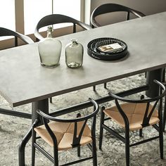 a table with two vases sitting on top of it and some chairs around it