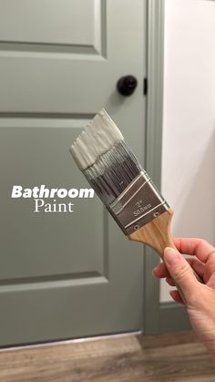 a person holding a paint brush with the words bathroom paint on it in front of a door