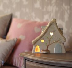 a small house sitting on top of a wooden table next to pillows and a pillow