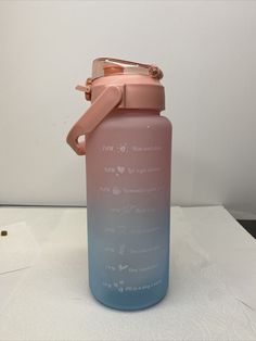 a pink and blue water bottle sitting on top of a white tablecloth covered counter