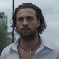 a man with long hair and beard wearing a white shirt is staring at the camera