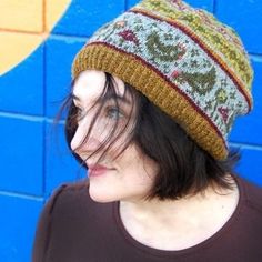 a woman wearing a knitted hat standing in front of a blue wall