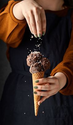 a woman is holding an ice cream cone with chocolate and sprinkles on it