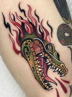 a close up of a tattoo on a person's leg with a dragon and snake