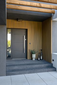 the entrance to a modern home with potted plants