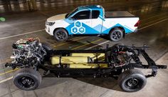 an off - road vehicle is parked next to a truck with the engine on it's flatbed