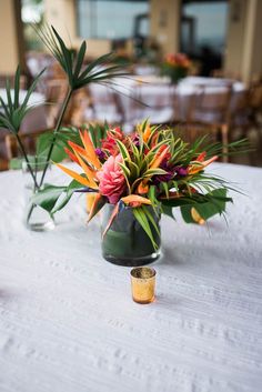 two vases filled with flowers sitting on top of a white tablecloth covered table