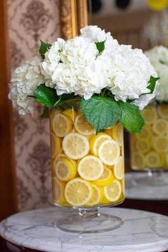 two vases filled with lemon slices and white hydrangeas on top of a table