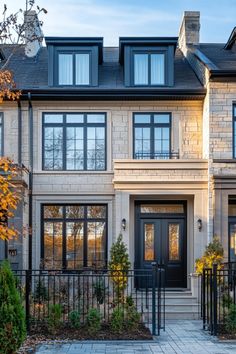 the front entrance to a two story house with black iron fence and gated entry way