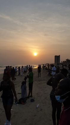 many people are on the beach at sunset or sunrise time as the sun goes down