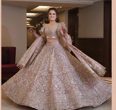 a woman in a gold and white lehenga is posing for the camera with her hands on her hips