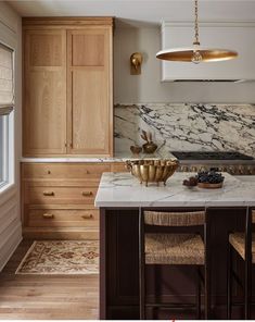 a kitchen with marble counter tops and gold accents on the cabinets, along with wooden stools