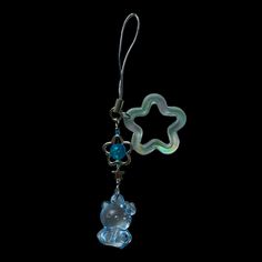 a glass bear with a star hanging from it's back end on a black background