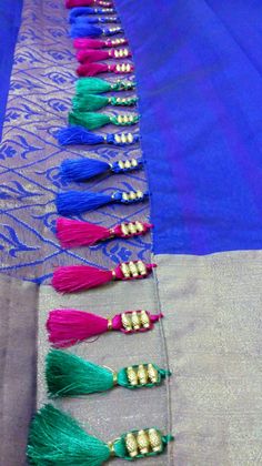 several tassels are lined up on a blue and gray table cloth with gold beads