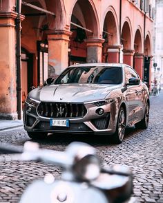 a silver car parked on the side of a road next to a tall brick building