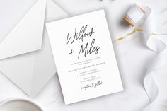 the wedding stationery is laid out on top of an envelope and some white ribbons