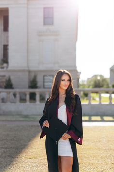 a woman standing in front of a large building wearing a black coat and white dress