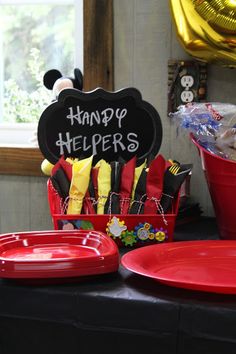 a mickey mouse themed birthday party with red plates and black chalkboard sign that says happy helpers