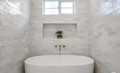 a white bath tub sitting under a window in a bathroom