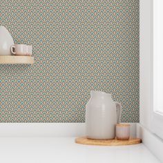 a white vase sitting on top of a counter next to a cup and saucer