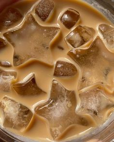 ice cubes are in a glass container filled with brown liquid and some other things