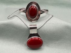 "Taxco Vintage Jewelry  Sterling Silver Cuff Bracelet with large red oval cabochon. Simple yet elegant geometric design.  Sterling Silver pendant with large red oval cabochon and huge bale. Sterling Silver chain.  The bracelet and pendant are from different silversmiths but they match nicely.  Bracelet  Marked:  TN-15. Mexico. 925.  Measures: Fits up to size 6 1/2\" wrist (see pic) Inside diameter: 2 1/2\" Opening:  1\" Top of bracelet:  1 1/2 x 1\" Red stone:  1\" x 5/8\" Weight:  31 grams.  Pe Modern Red Cabochon Jewelry, Red Sterling Silver Oval Cabochon Jewelry, Red Oval Cabochon Jewelry With Polished Finish, Red Oval Jewelry With Polished Finish, Handmade Red Oval Cabochon Jewelry, Red Oval Pendant Jewelry With Polished Finish, Large Pendant Necklace, Vintage Mexico, Wide Cuff Bracelets