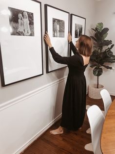 a woman is placing pictures on the wall