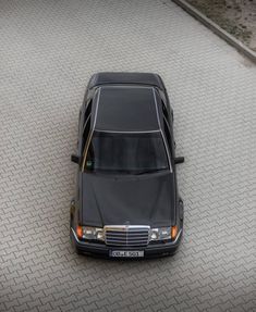 a black car parked on top of a parking lot next to a street with no cars