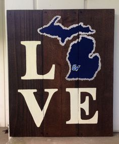 a wooden sign that says love with the shape of michigan on it's side