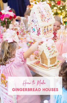 two girls are decorating gingerbread houses in front of a christmas tree