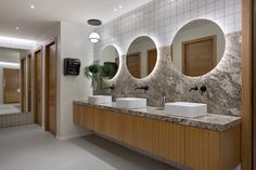 a bathroom with three sinks and mirrors on the wall