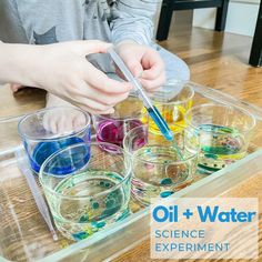 a young boy is doing science experiment with oil and water in glass containers on a table