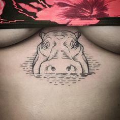 a woman's stomach with a hippoceros tattoo on her chest and behind her is a pink flower