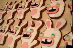 many decorated cookies with pink and white frosting on top of each other, including an animal's face