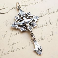 an ornate silver cross on top of a piece of paper