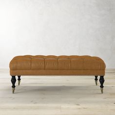 an upholstered leather bench with wooden legs and nail polishing on the legs