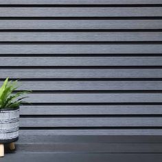 a potted plant sitting on top of a wooden table next to a black and white wall