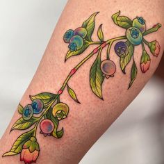 a close up of a person's leg with flowers on it and leaves around the legs