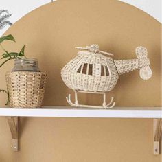 a white shelf topped with a basket and potted plant next to a birdcage