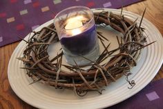 a candle is placed in the middle of a grapevine wreath on a white plate