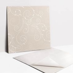 a white card and envelope on a white surface with an intricate design in the middle