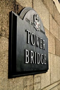 the city of london tower bridge sign is displayed on a building's side wall